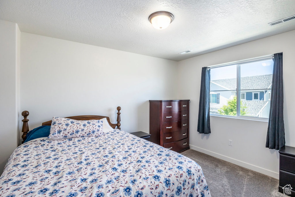 Bedroom featuring a textured ceiling and dark colored carpet