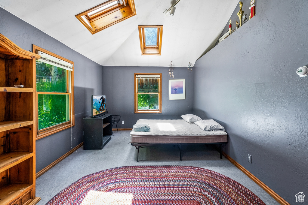 Bedroom featuring vaulted ceiling with skylight and carpet flooring