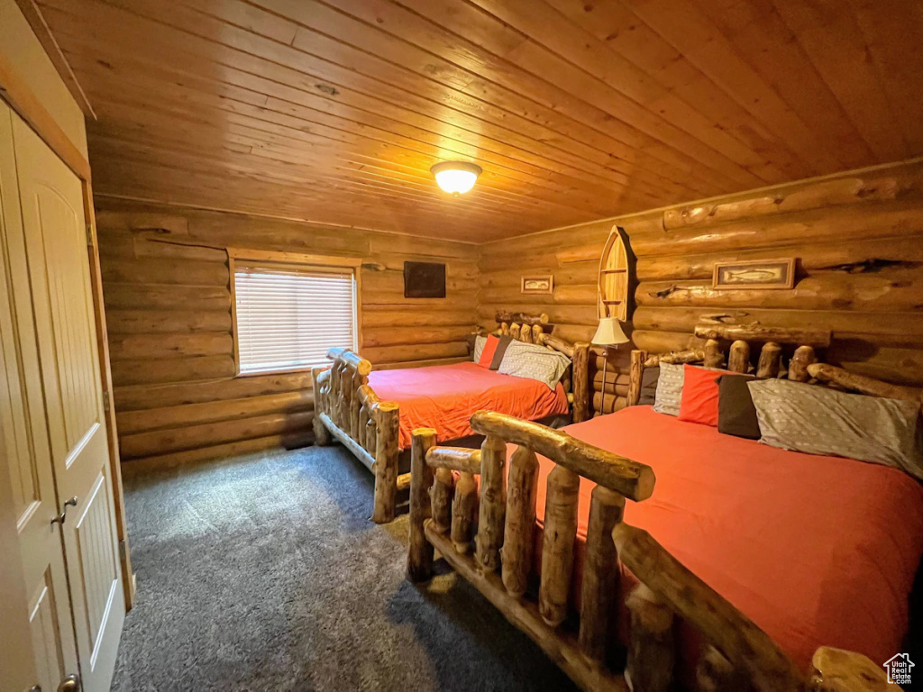 Bedroom with carpet floors, log walls, and wooden ceiling
