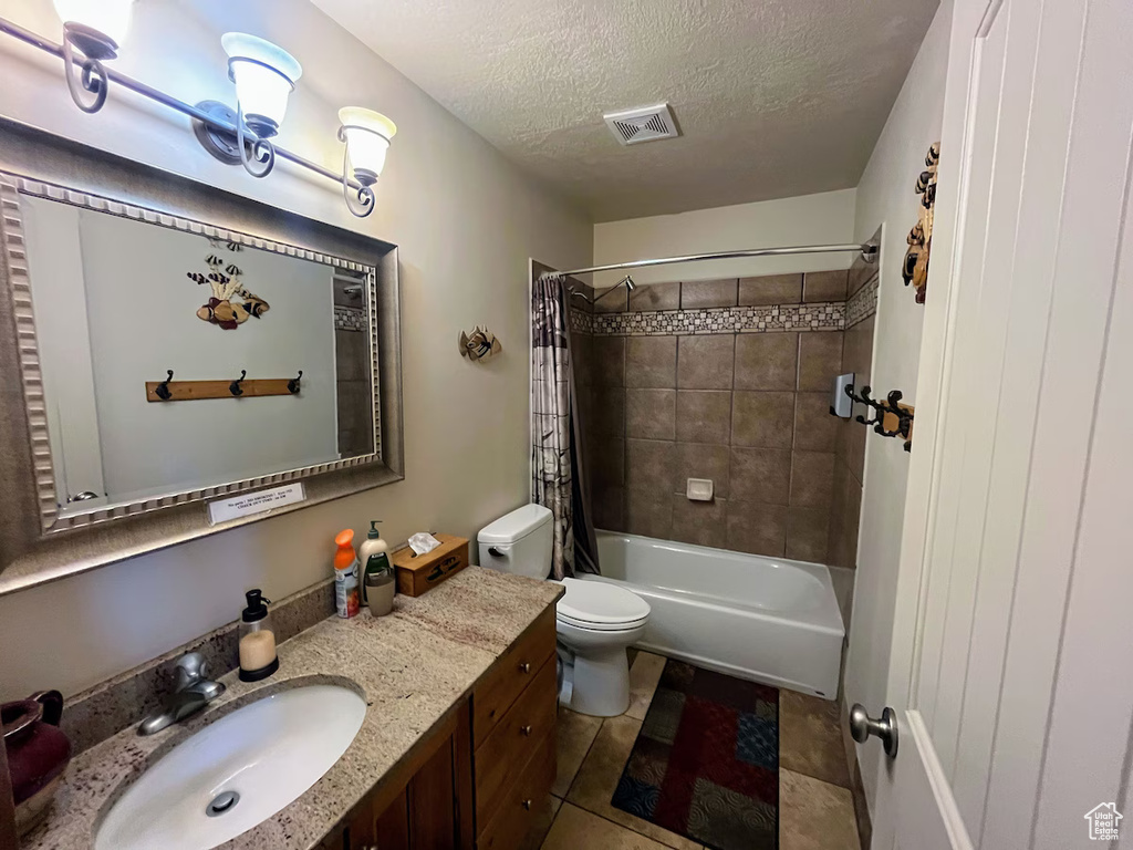 Full bathroom featuring toilet, tile floors, vanity, a textured ceiling, and shower / tub combo with curtain