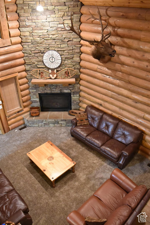 Unfurnished living room featuring carpet flooring, log walls, and a fireplace