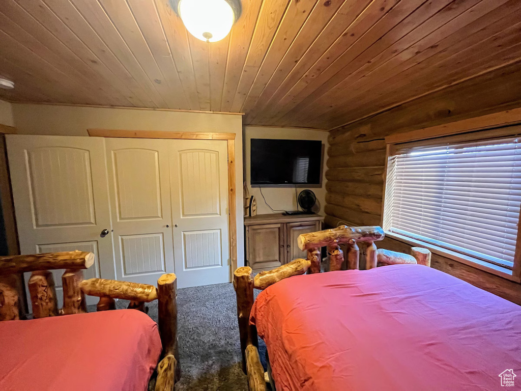 Bedroom featuring a closet, wood ceiling, and log walls