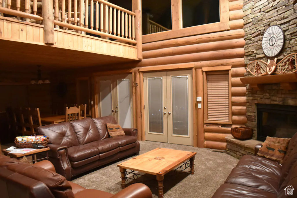 Living room featuring carpet, french doors, a fireplace, and rustic walls
