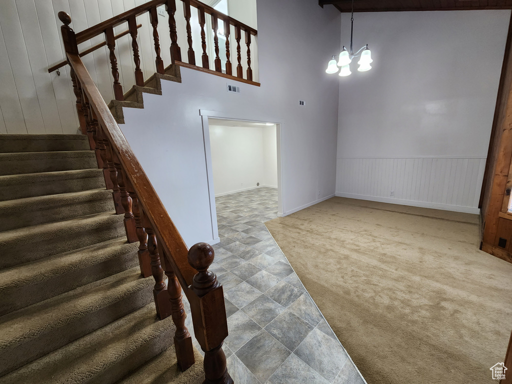 Stairs with carpet, a high ceiling, and a chandelier