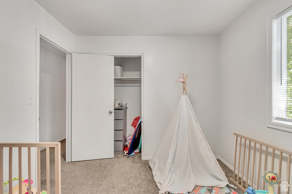 Bedroom with light carpet, a nursery area, and a closet