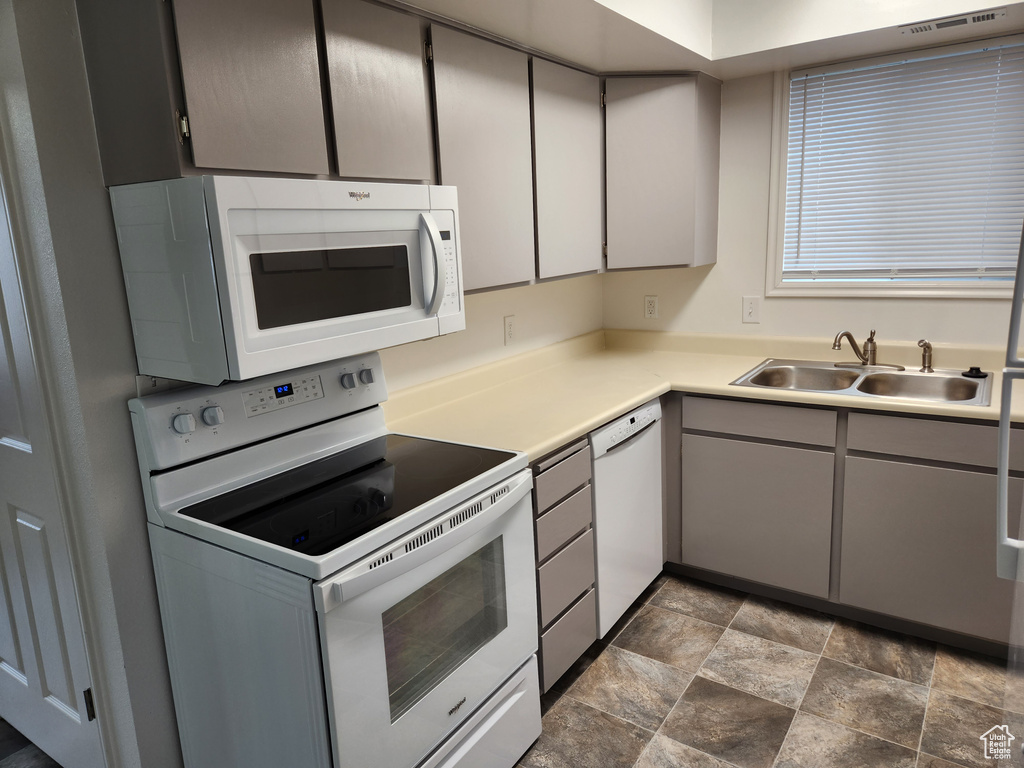 Kitchen featuring sink, dark tile flooring, and white appliances