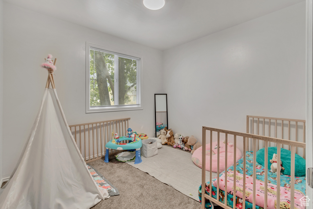 Bedroom featuring a nursery area and carpet