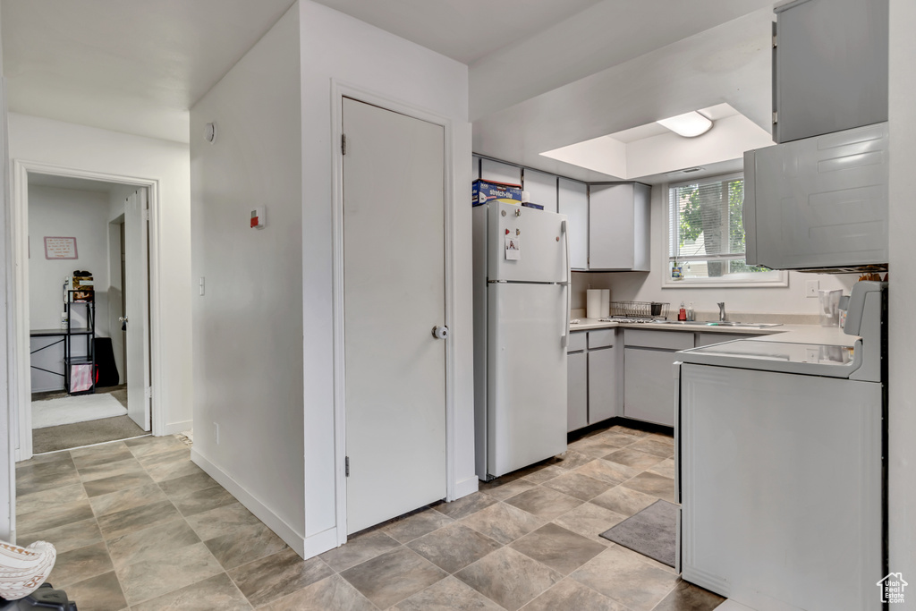 Kitchen with light tile flooring, range, and white refrigerator