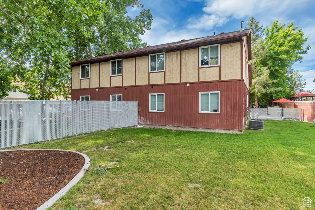 Rear view of property featuring a yard and central AC