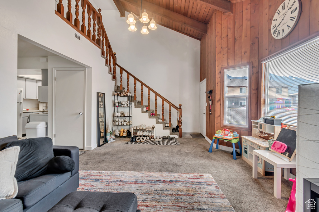 Carpeted living room featuring beamed ceiling, high vaulted ceiling, wood ceiling, and an inviting chandelier