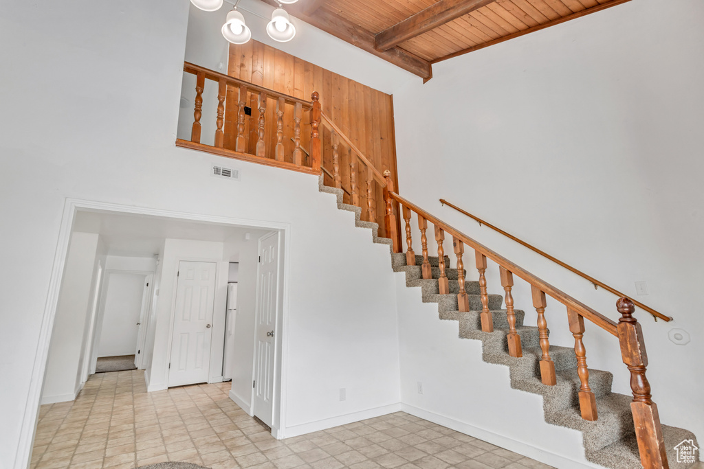 Staircase featuring wooden ceiling, a towering ceiling, and light tile floors