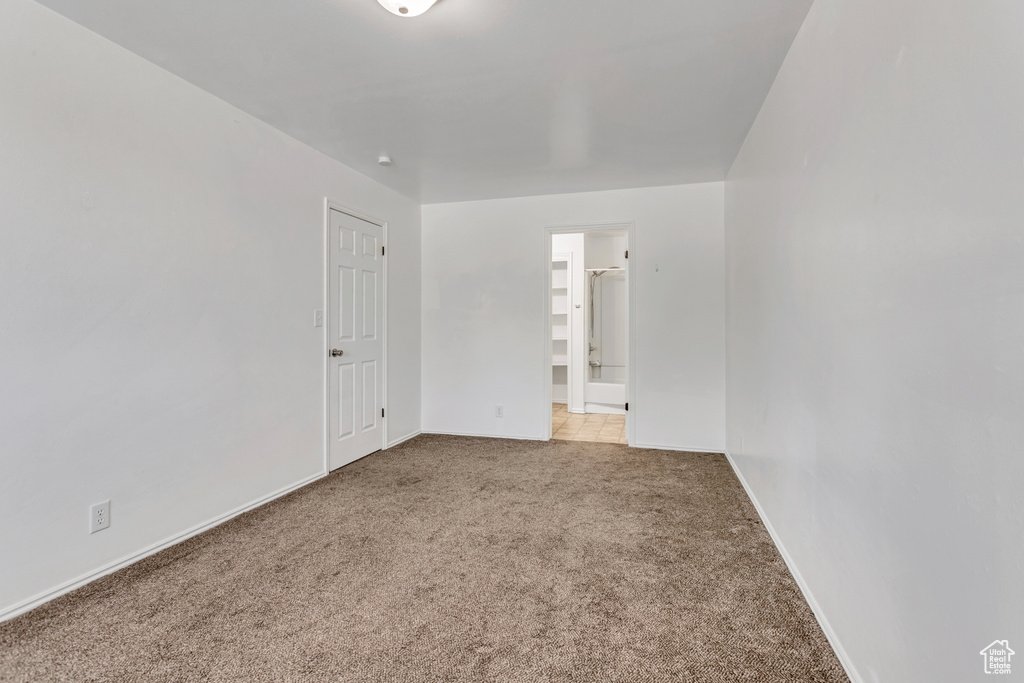 Unfurnished bedroom featuring a closet, ensuite bathroom, and light colored carpet