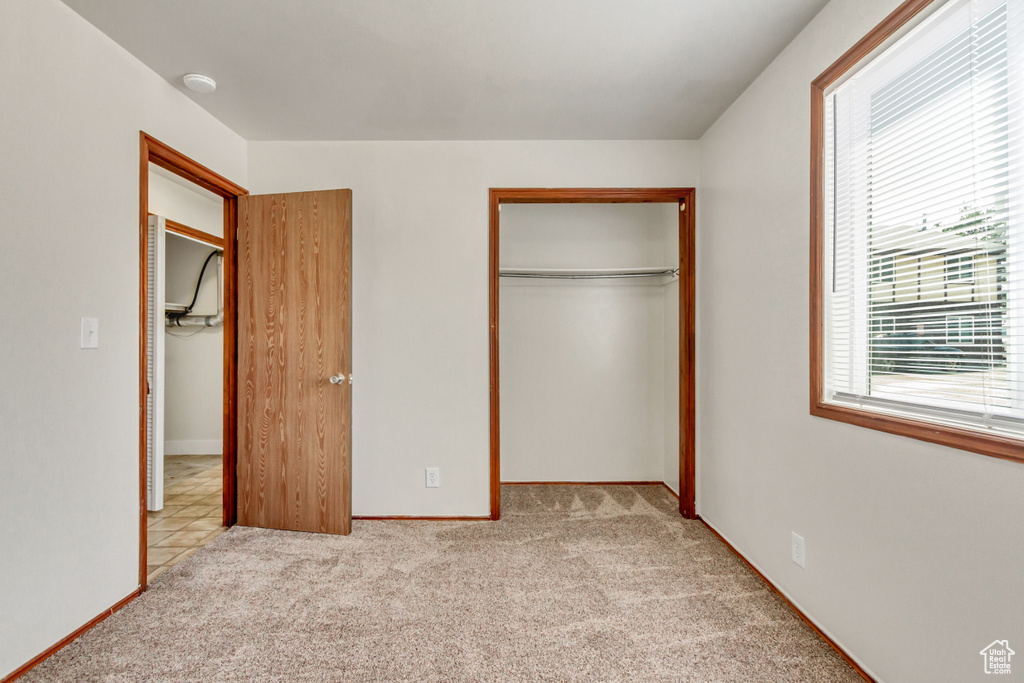 Unfurnished bedroom with light carpet and a closet