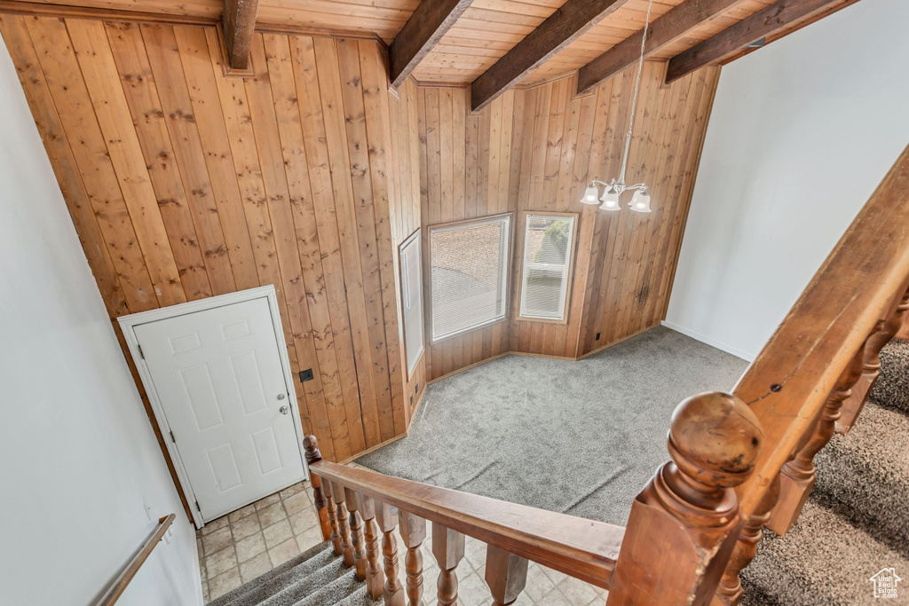 Foyer entrance featuring beam ceiling, wooden ceiling, wooden walls, and carpet floors