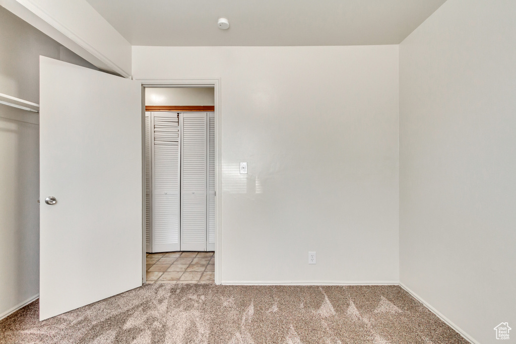 Unfurnished bedroom featuring a closet and light colored carpet