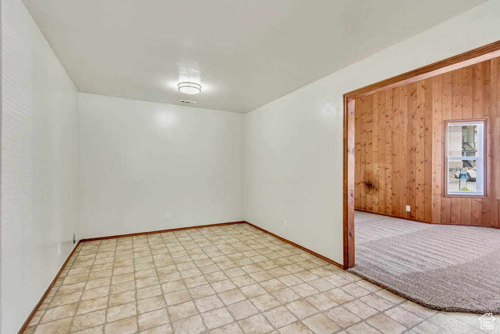 Unfurnished room with wooden walls and light tile patterned floors