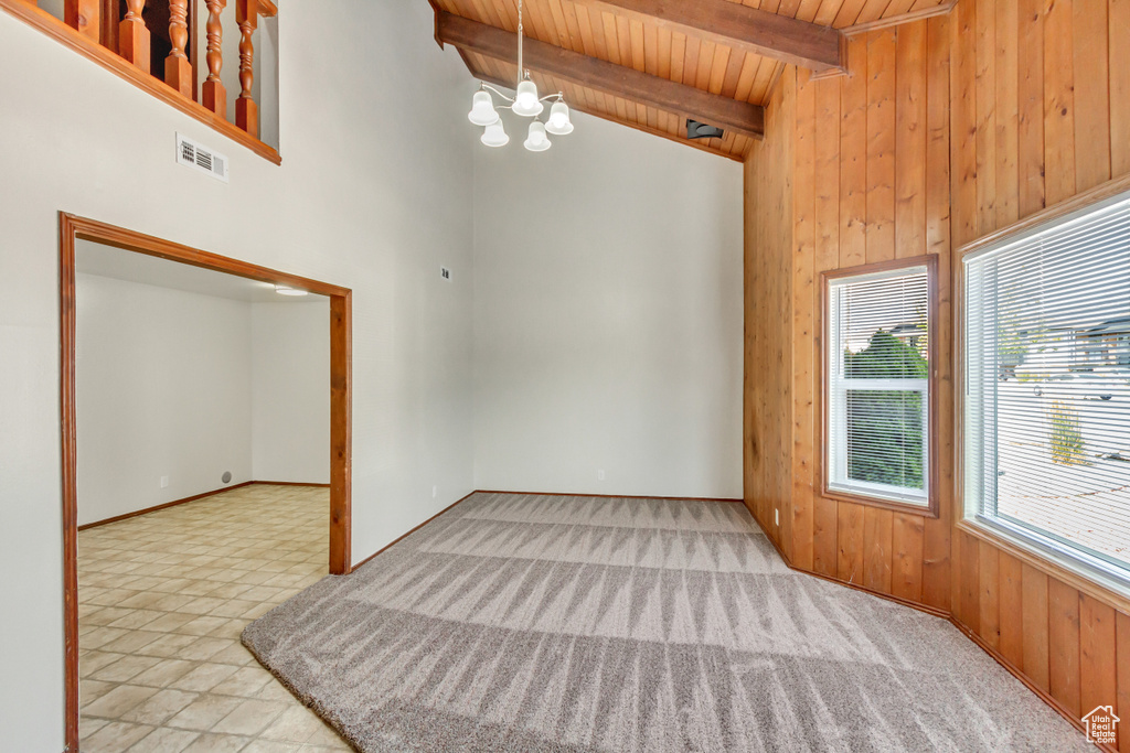 Spare room with a notable chandelier, wooden ceiling, high vaulted ceiling, beamed ceiling, and light carpet