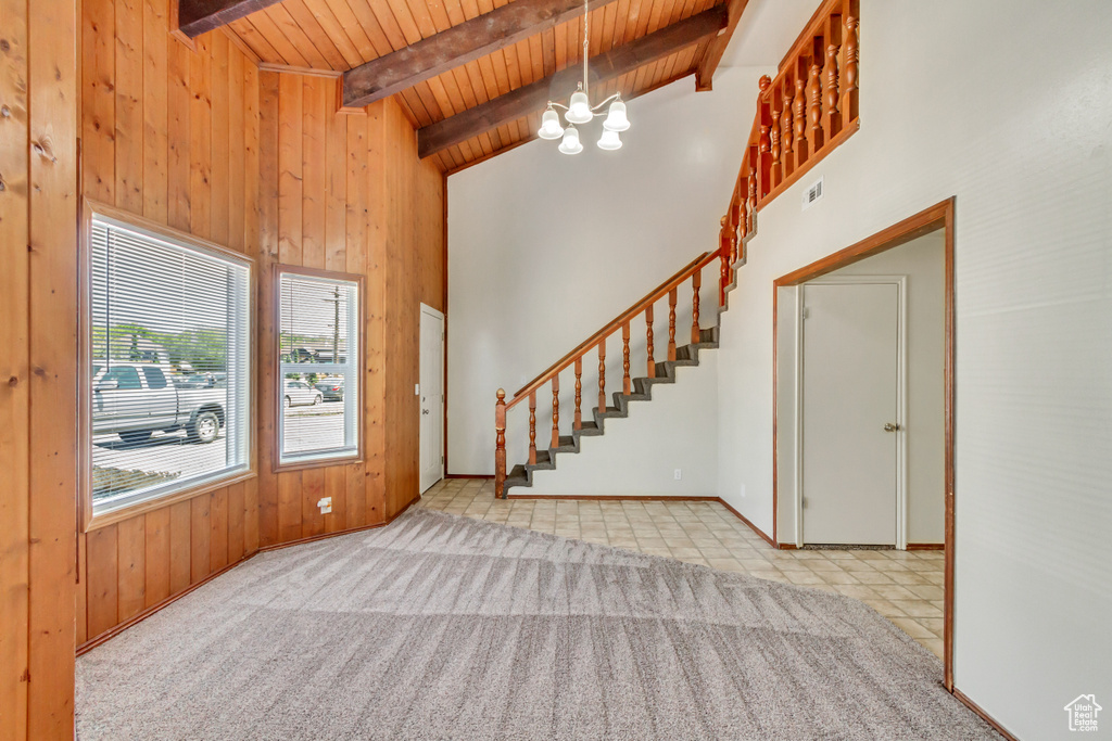 Carpeted foyer entrance featuring high vaulted ceiling, beamed ceiling, wooden ceiling, and a notable chandelier