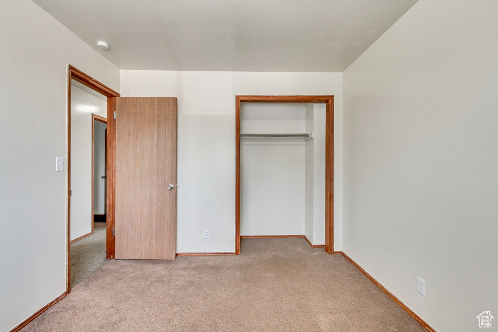 Unfurnished bedroom featuring a closet and light colored carpet