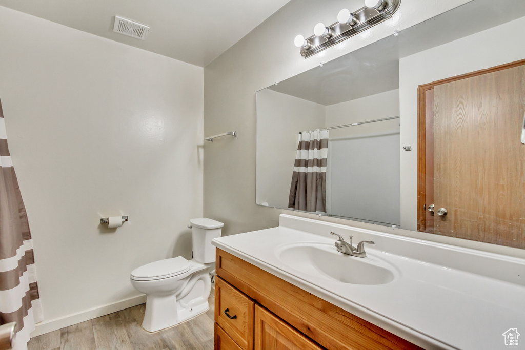 Bathroom with hardwood / wood-style flooring, toilet, and vanity