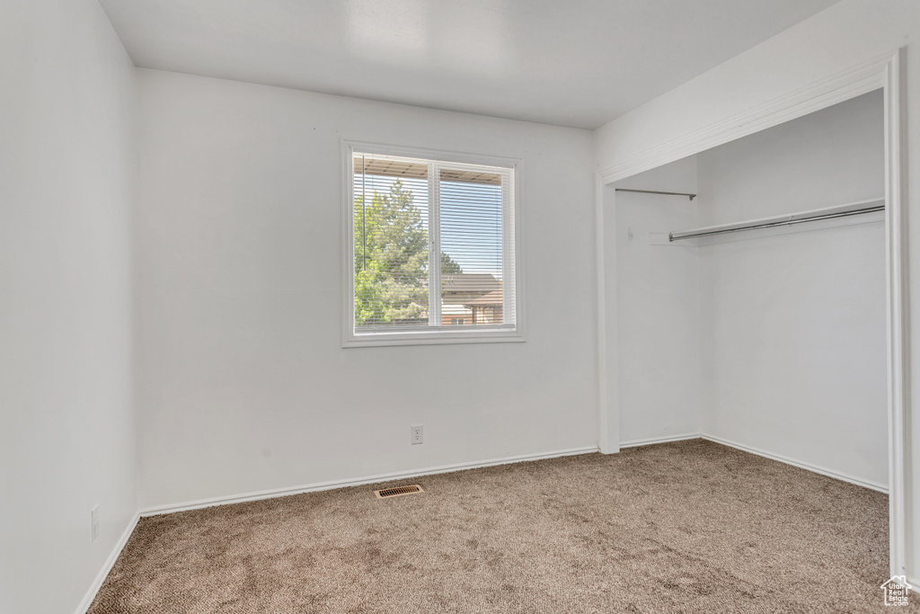 Unfurnished bedroom featuring carpet flooring and a closet