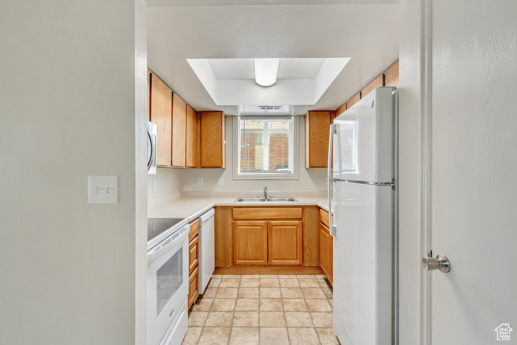 Kitchen featuring sink, white appliances, and light tile patterned floors