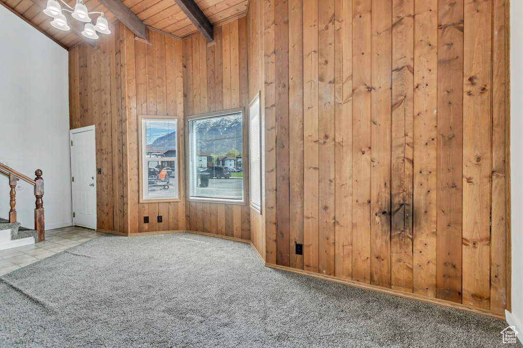 Empty room featuring tile floors, beam ceiling, wood walls, and wood ceiling