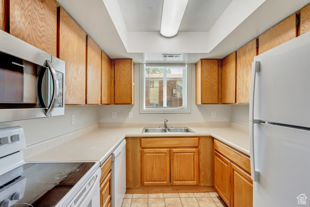 Kitchen with sink, light tile patterned floors, and white appliances