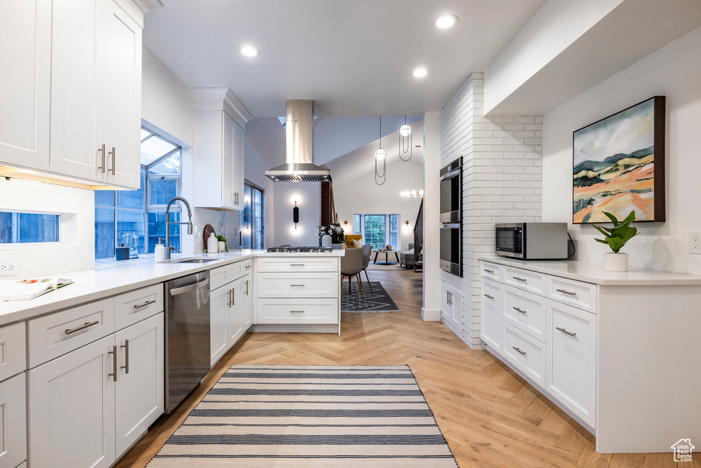 Kitchen featuring light parquet floors, extractor fan, white cabinets, sink, and appliances with stainless steel finishes