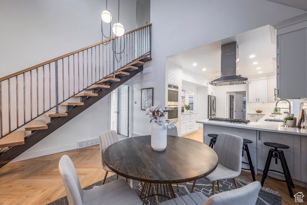 Dining room featuring a towering ceiling, light parquet flooring, and sink