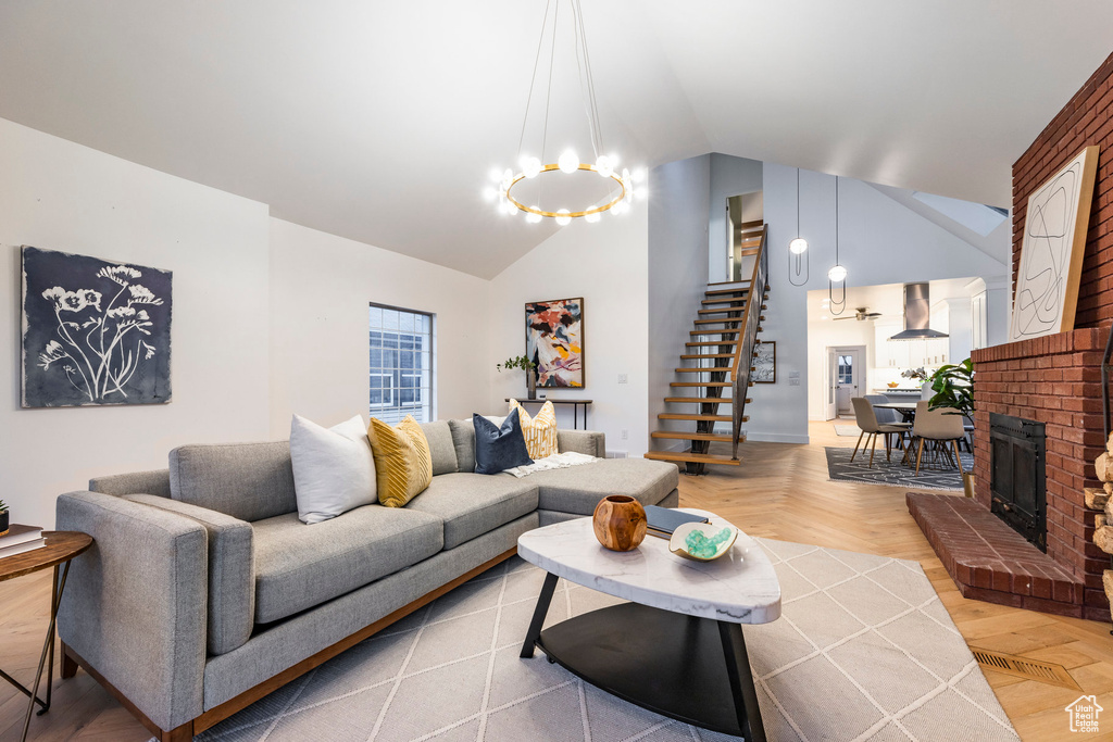 Living room featuring parquet floors, a chandelier, a brick fireplace, and lofted ceiling