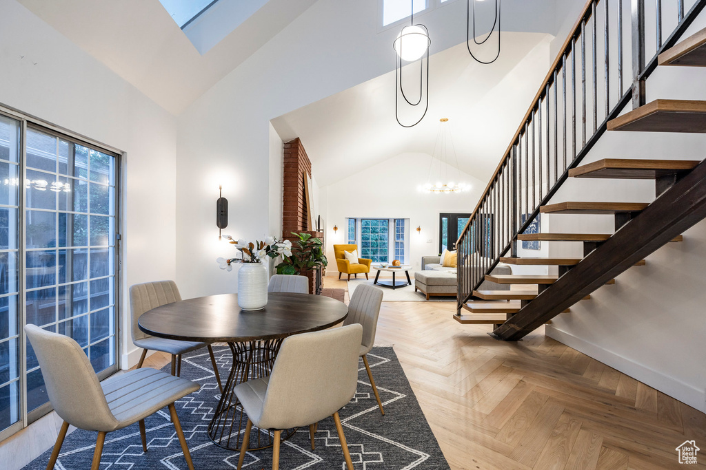 Dining space with a skylight, an inviting chandelier, a towering ceiling, and parquet floors