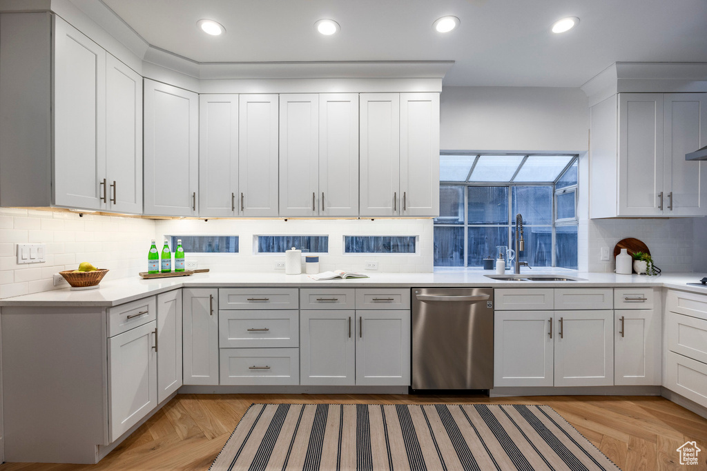 Kitchen featuring white cabinetry, tasteful backsplash, dishwasher, light parquet flooring, and sink