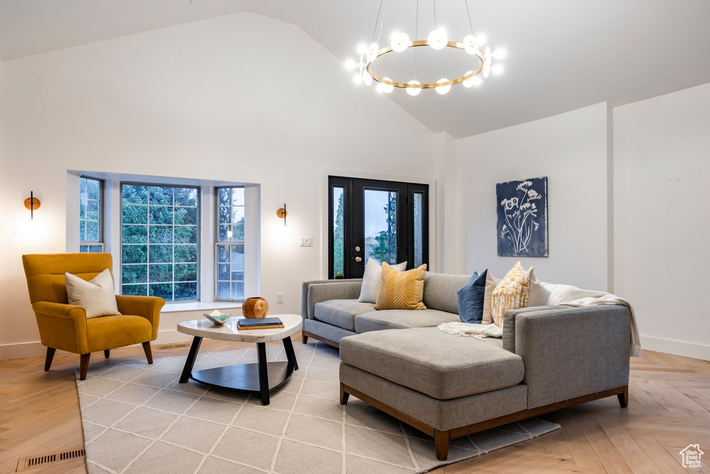 Living room with light parquet floors, an inviting chandelier, and high vaulted ceiling