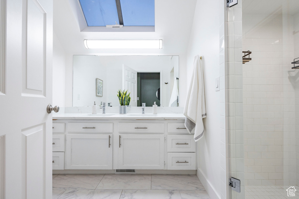 Bathroom featuring vanity, a tile shower, and tile patterned flooring