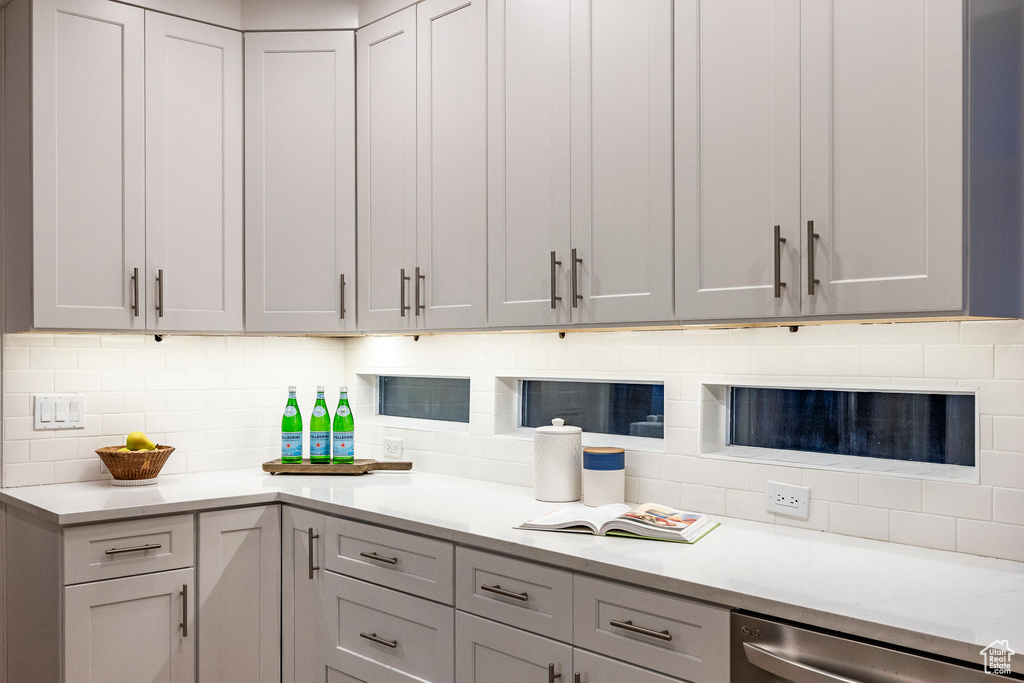 Kitchen with gray cabinets, dishwasher, and backsplash