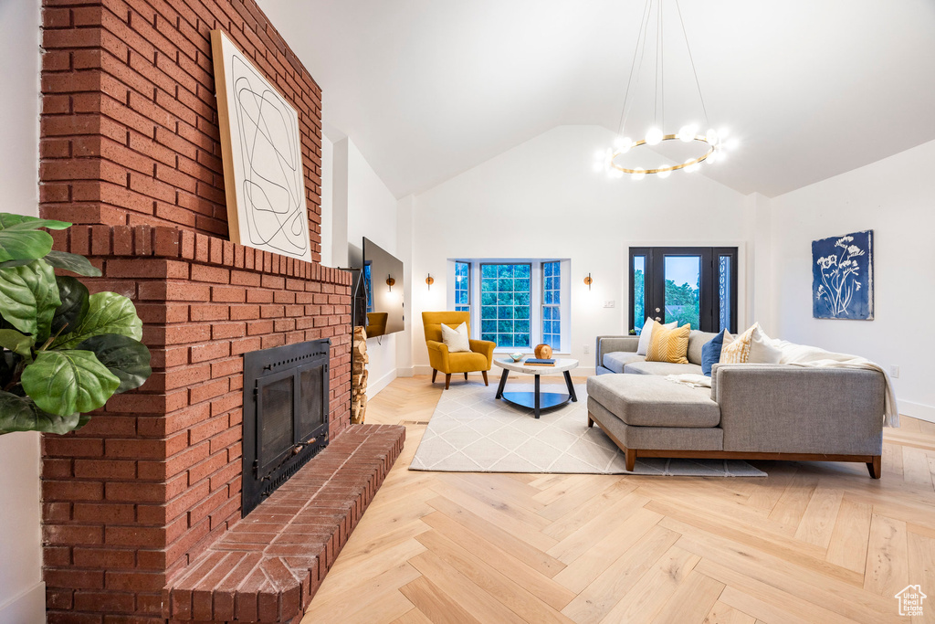 Living room featuring vaulted ceiling, brick wall, a fireplace, and light parquet flooring