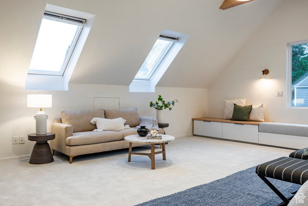 Carpeted living room featuring vaulted ceiling with skylight