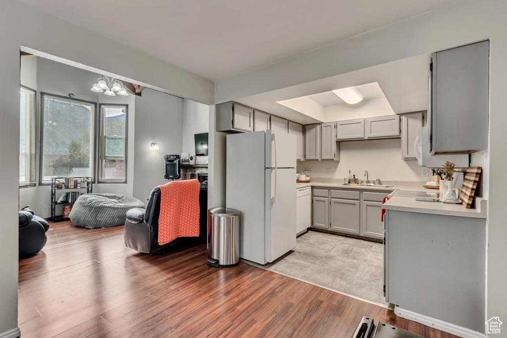 Kitchen with light hardwood / wood-style floors, sink, white appliances, and gray cabinets