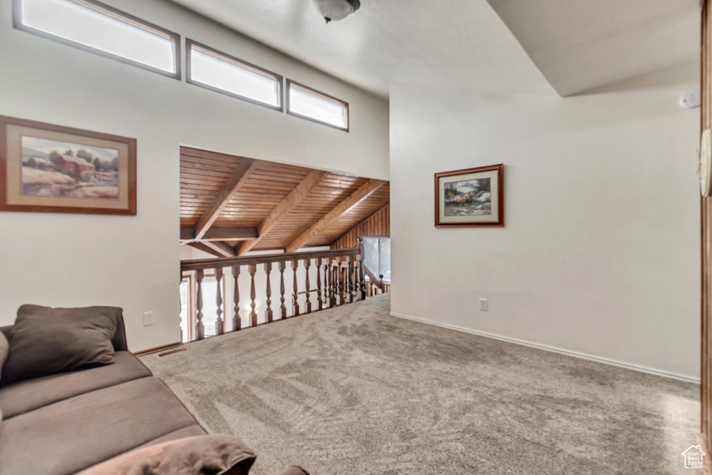 Carpeted living room featuring lofted ceiling with beams