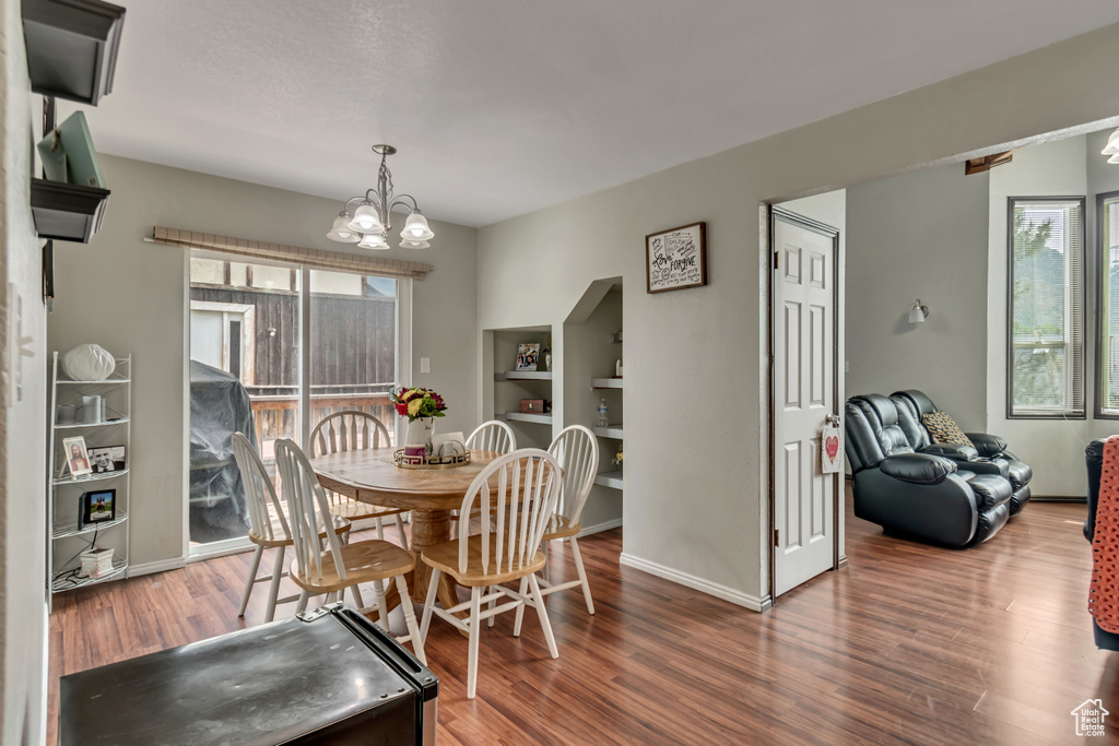 Dining space with a healthy amount of sunlight, wood-type flooring, and a notable chandelier