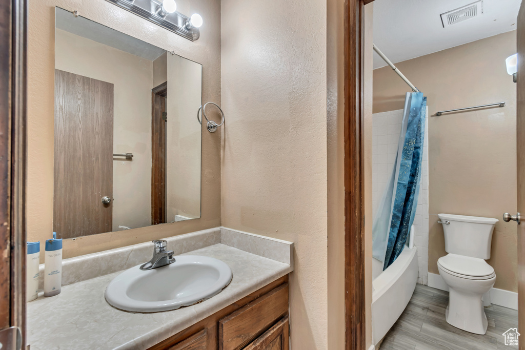 Full bathroom featuring wood-type flooring, vanity, toilet, and shower / tub combo