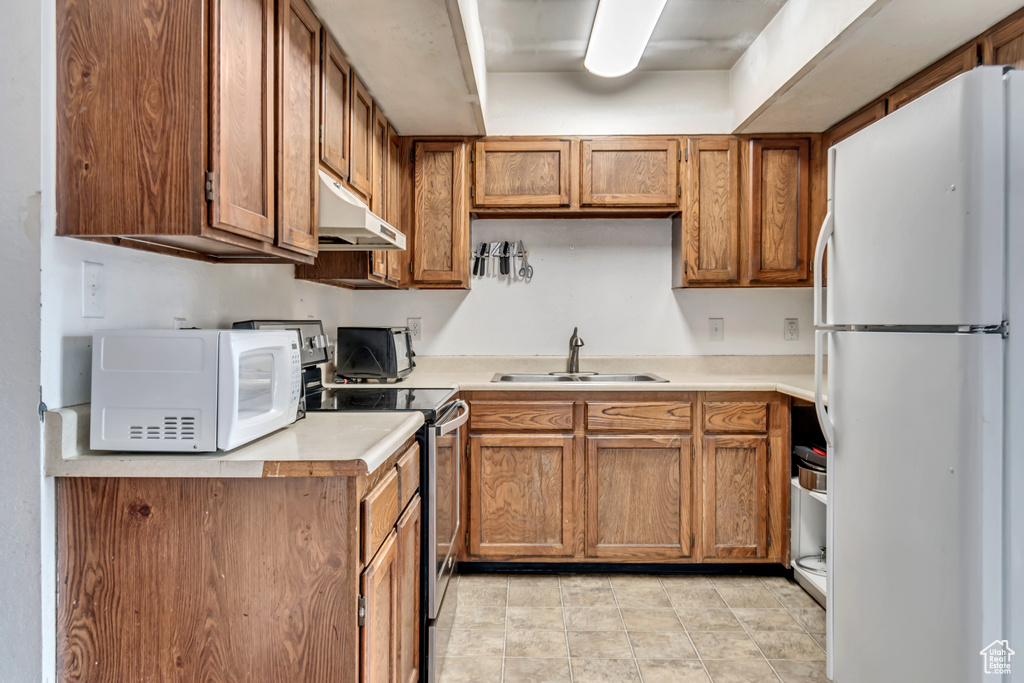 Kitchen with sink, white appliances, and light tile floors