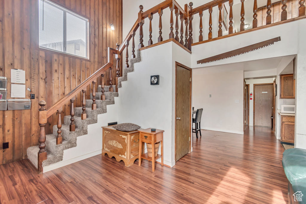 Stairs featuring wood walls, a towering ceiling, and wood-type flooring