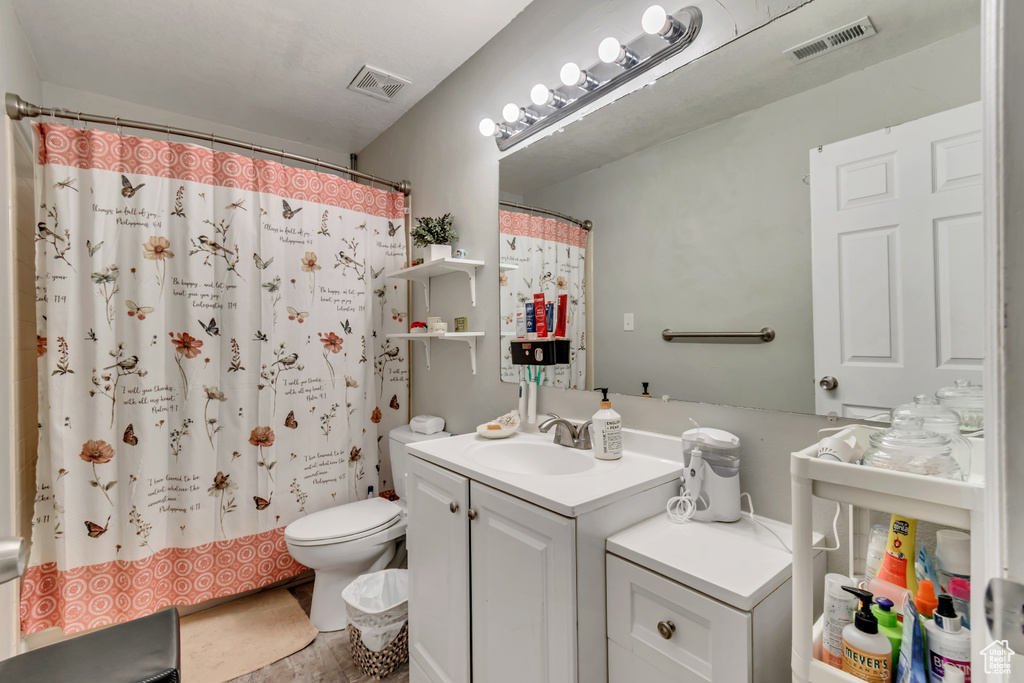 Bathroom featuring tile flooring, large vanity, and toilet