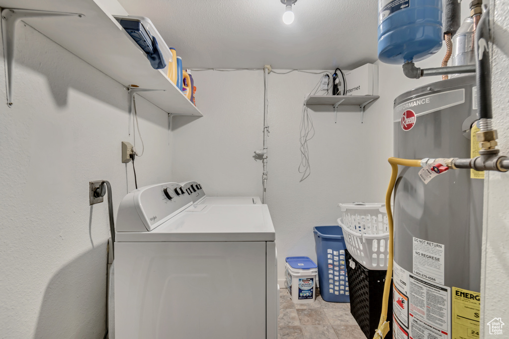 Clothes washing area featuring separate washer and dryer, gas water heater, and light tile floors