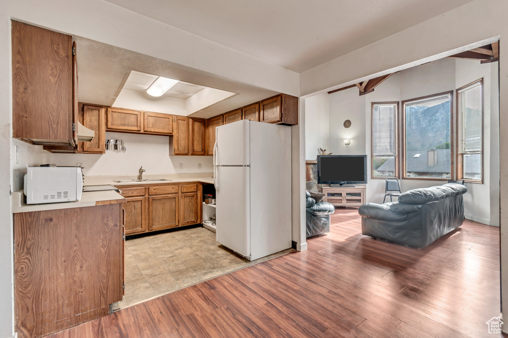 Kitchen featuring white appliances, exhaust hood, sink, and light hardwood / wood-style flooring