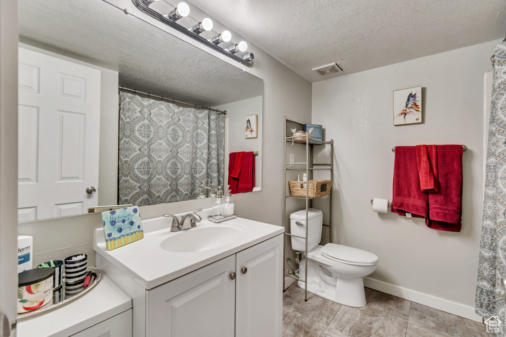 Bathroom featuring tile floors, toilet, a textured ceiling, and large vanity