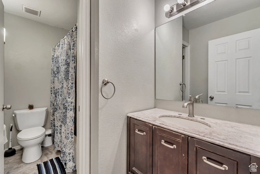 Bathroom with vanity with extensive cabinet space, toilet, and tile floors