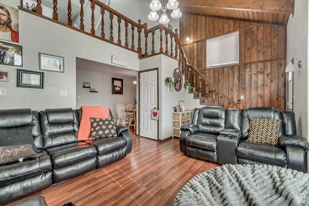 Living room featuring high vaulted ceiling, wooden walls, and hardwood / wood-style floors